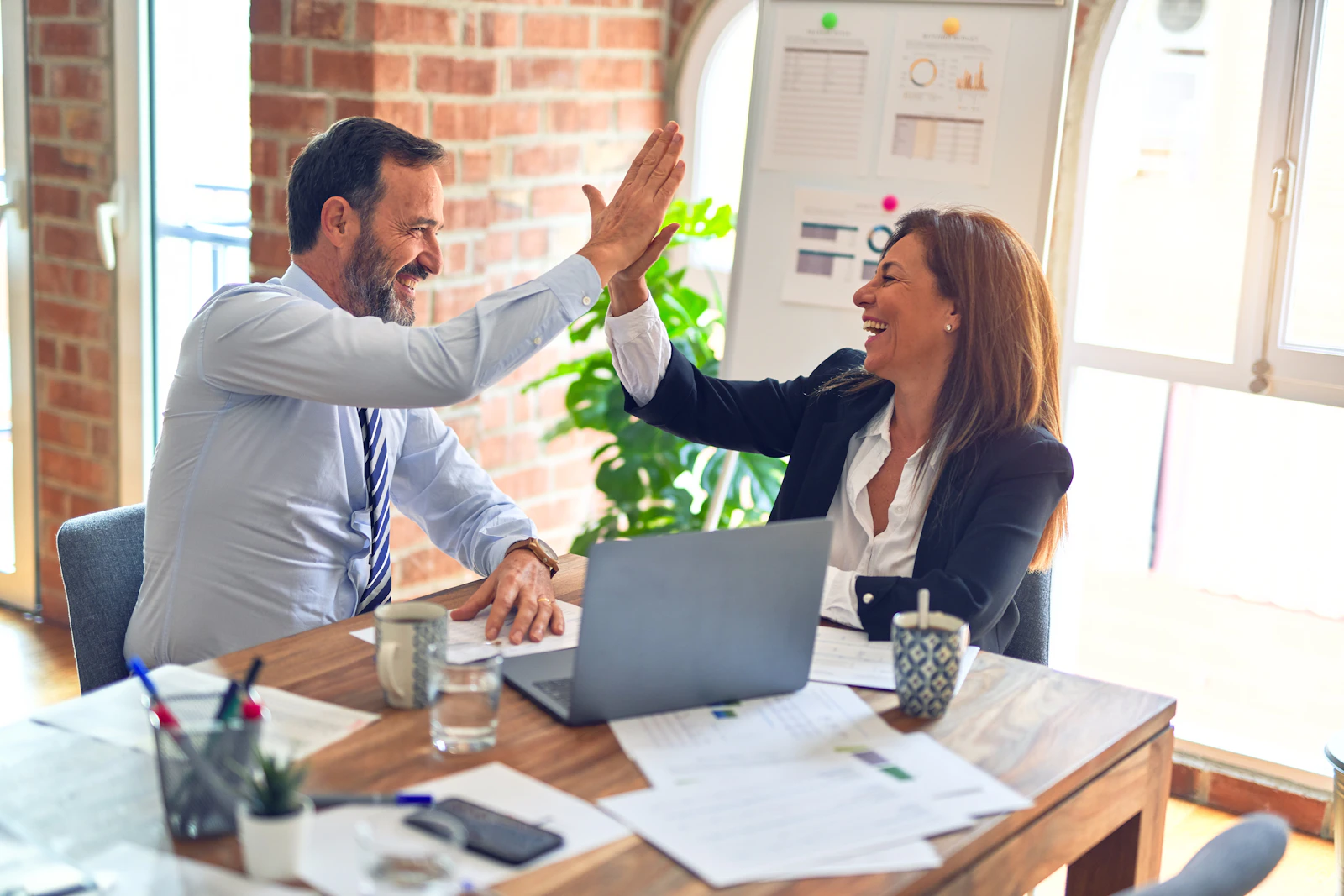 Two consultants celebrating a won bid in a bright office